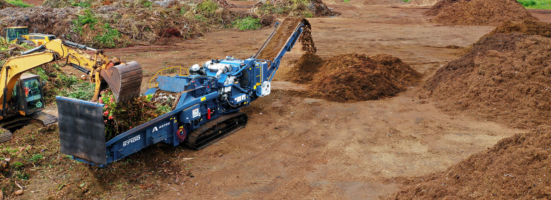 Astec Peterson 5710D Horizontal Grinder making compost from green waste in Hawaii with an loading excavator.